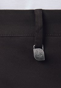 Czarny materiałowy pas w ramach wykończenia teksturowanego, z metalowym zapięciem z wygrawerowanym logo i kontrastującym detalem ściegów.