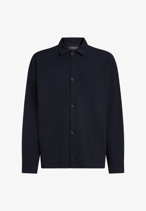 Tumši zila garām piedurknēm krekls no mīksta auduma, ar pogu aizdari priekšpusē, izteiktu apkakli un vienu kabatu uz kreisās krūšu puses.