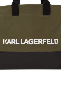 Borsa tote verde e nera realizzata in tessuto resistente, con una scritta bianca audace "KARL LAGERFELD" sul davanti. Spallacci neri robusti.