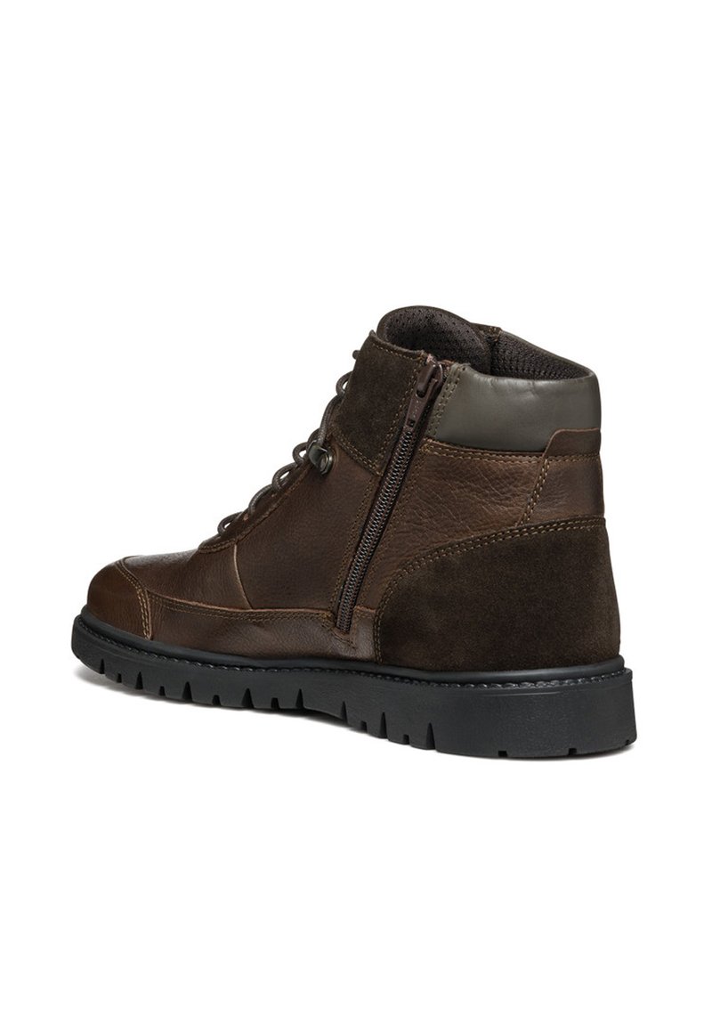 Bottines en cuir marron et en suede avec une semelle en caoutchouc, présentant une fermeture éclair sur le côté et un bout rond. Design robuste adapté à un usage décontracté.