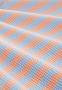 Textil con rayas onduladas alternas en azul claro y melocotón. La tela tiene una textura acanalada, creando profundidad e interés visual.