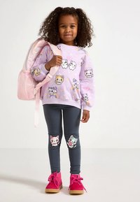 Ljuslila sweatshirt med tecknade djur, kombinerad med mörkgrå leggings med djurdetaljer på knäna. Klarrosa skor och ryggsäck.