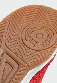 Semelle en caoutchouc avec un motif marron, non marquant. Design en zigzag texturé et emblème circulaire au centre. Détail de bord blanc.