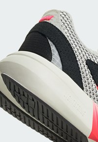 Gray sneaker with a mesh upper, black accents, and a textured black sole. Features pink branding and a light-colored midsole.