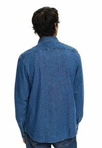 Camisa de mezclilla en azul medio con un ajuste casual, mangas largas y puños abotonados. Presenta un collar clásico y detalles de dobladillo redondeado.