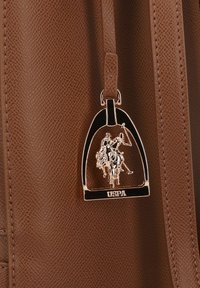 Borsa in similpelle marrone con targhetta metallica USPA a forma di staffa, con un design in rilievo di un giocatore di polo.