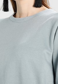 Sudadera azul clara con cuello redondo, textura de tela suave y sin patrones ni adornos visibles.