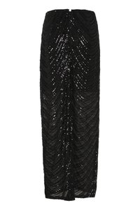 Black sequined long skirt with a fitted silhouette, featuring a chevron pattern and a back slit for ease of movement. Soft texture.