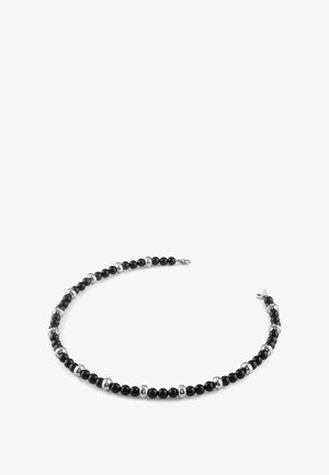 Collana di perline nere con accenti sferici alternati in tonalità argento. Texture liscia con design curvato, fissata da una chiusura a un'estremità.