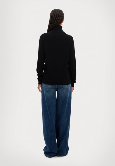 Black mock turtleneck sweater with long sleeves paired with loose-fitting dark blue denim jeans. The fabric appears soft and textured.