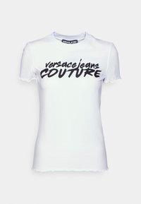 Vit kortärmad t-shirt med rund hals, prydd med fet svart text "versacejeans COUTURE", och en något fransad fåll.