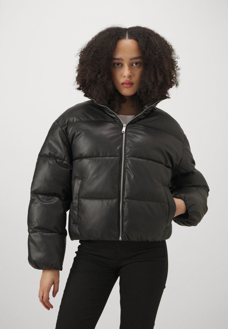 Svart pufferjakke i syntetisk materiale, kort design, glidelås, oversized passform, med quiltede seksjoner og høy krage.