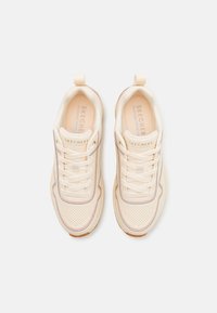 Skechers tenisky z jemné béžové kůže s perforovaným designem, bílými tkaničkami a jemným hnědým akcentem podél podešve.