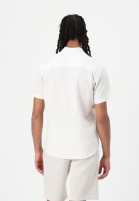 Korte mouwen, lichtbeige shirt met een witte kraag, met een rechte zoom en een losse pasvorm, gecombineerd met gestreepte beige shorts.