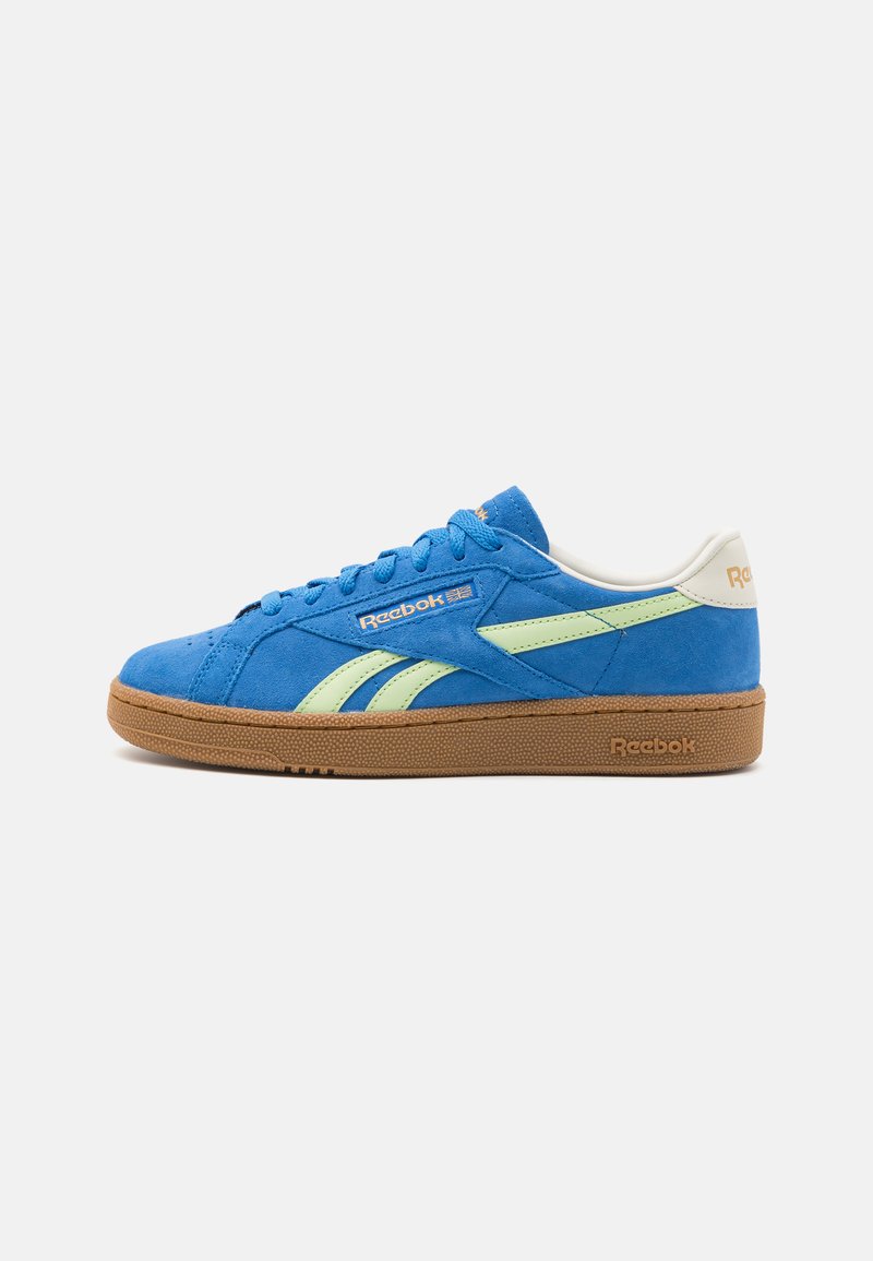 Sneaker blu in suede con accenti verdi, suola in gomma testurizzata e lacci abbinati. Presenta il marchio Reebok sul lato e sul tallone. Design a punta rotonda.