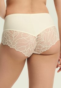 Beżowe majtki hipsterskie z gładkim pasem i misterną koronkową nakładką w kwiatowy wzór na tylnej części.