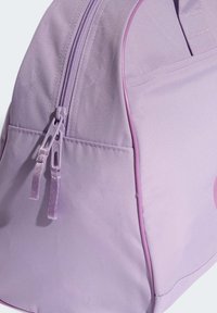Sac à dos en tissu violet avec une texture lisse, comportant des double fermetures éclair, un bord rose contrastant et une poche externe.