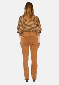 Blouse à carreaux bruns avec des manches bouffantes, assortie à un pantalon en velours côtelé beige. Texture lisse, design à jambe droite, poches arrière sur le pantalon.