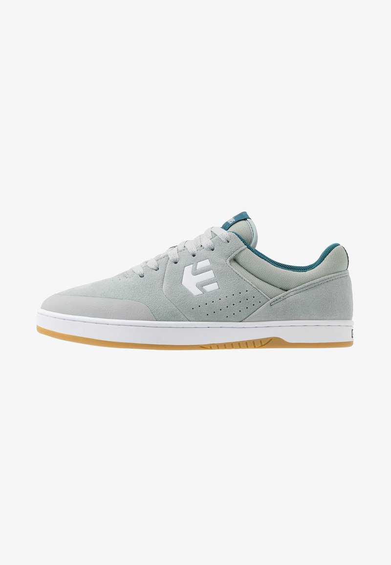 Světle šedé semišové skate boty s bílým logem, perforovanou stranou a akcenty v teal barvě. Bílá gumová podrážka s hnědou gumovou vnějším podrážkou.