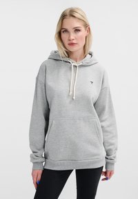 Grå hoodie i mjukt material, med en framficka, dragsko i huvan och en liten logotyp på bröstet. Avslappnad passform med ribbade ärmslut.