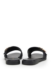 Zwarte slide sandalen met gladde leren banden en een gestructureerde afwerking. Voorzien van een metalen accent op de band en een platte rubberen zool.