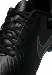 Black soccer cleat with textured leather upper, black laces, and teal Nike logo. Features distinct contour lines on the surface.