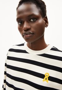 Gestreept sweatshirt met zwart-witte horizontale strepen, geribbelde crew-halslijn en een gele geborduurde accent in de vorm van een lint.