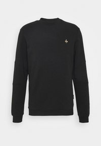 Schwarzer Hoodie aus weichem Stoff, mit ribbelndem Rundhals, langen Ärmeln und einem kleinen goldenen Fleur-de-Lis-Akzent auf der Brust.