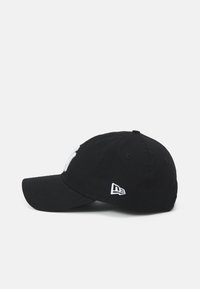Mustan sirbiga baseballi müts, millel on kumer serv, esiküljel valge logo tikand ja küljel väike logo.
