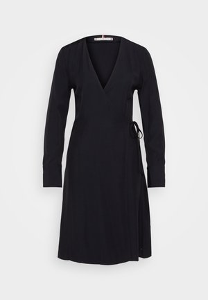 Μαύρο φόρεμα με τύλιγμα, μακριά μανίκια, ντεκολτέ σε V, και ζώνη στη μέση με κορδόνι. Λείος ύφασμα και κομψή σιλουέτα.