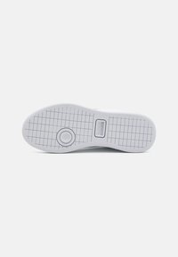 Fehér sneaker talp rácsos mintával és kör alakú dizájnnal az elején, a középen található "LACOSTE" felirattal ellátott téglalap alakú logóval.