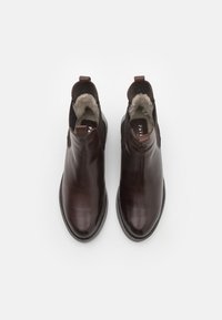 Bottines en cuir marron avec une finition lisse, des panneaux latéraux élastiques et une doublure beige douce. Dotées d'une languette pour un enfilage facile.