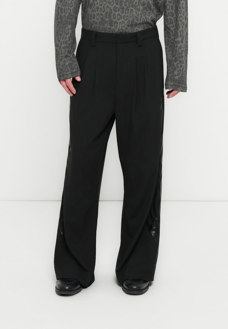 Μαύρο παντελόνι φαρδιάς γραμμής με πιέτες, διαθέτει διάφανα πλαϊνά πάνελ. Κατασκευασμένο από λείο ύφασμα, έχει μινιμαλιστικό σχεδιασμό και άνετη εφαρμογή.