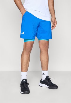 Plave sportske kratke hlače od laganog materijala, s unutarnjom podstavom u tirkiznoj boji i bijelim Adidas logotipom na lijevoj strani.