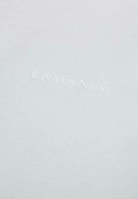 Biała tkanina z subtelnym, wytłaczanym napisem "LAMANIA" w centralnej części, tworzącym efekt teksturowanego logo marki.