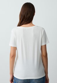 T-shirt bianco a maniche corte realizzato in tessuto morbido. Presenta un collo arrotondato e una vestibilità comoda, con una texture liscia e leggera.