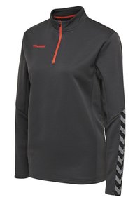 Pull-over de sport gris foncé à manches longues avec fermeture éclair rouge au quart, logo hummel rouge sur la poitrine et motif chevrons noir et gris sur la manche droite.