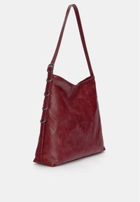 Rote Leder-Schultertasche mit weicher Textur, dreieckiger Form und einem langen verstellbaren Tragegurt, der auf einer Seite dekorative Metallringe aufweist.