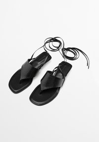 Zwarte platte sandalen met een bovenwerk van textuurleer, V-vormig ontwerp en slanke enkelbandjes. Vierkante neus en minimalistische stijl.