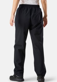 Black waterproof pants with an elastic waistband, tapered cuffs, and reflective accents, designed for outdoor activities.