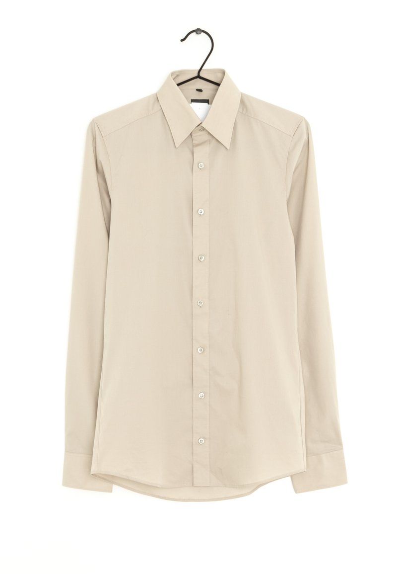 Lichtbeige, langemouwen overhemd aan een hanger, met een puntige kraag, sluiting met knopen aan de voorkant en een gladde, iets gestructureerde stof.