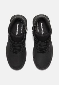 Czarne botki za kostkę z teksturowanego materiału, wzmocnionym noskiem i sznurowaniem. Posiadają wyściełany kołnierz oraz wkładki z logo Timberland.