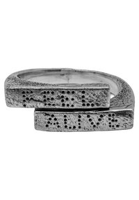 Silver dubbelring med en texturerad yta och punkter som liknar braille längs kanterna, formad med en modern geometrisk design.