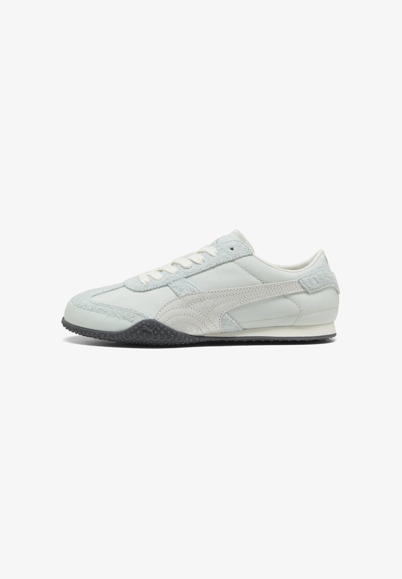 Λευκό sneaker με χαμηλό προφίλ, επενδύσεις από σουέντ, ραμμένη πλευρική ρίγα, λευκά κορδόνια και μαύρη υφή καουτσούκ σόλα.