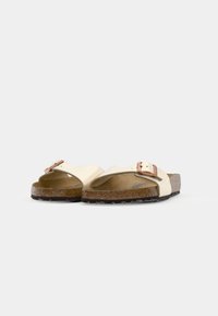 Beige sandaler med to brede remmer, en med en metallisk spenne. Korksåle og teksturert svart gummisåle gir godt grep.