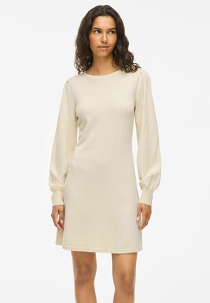 Beige long-sleeve dress made of soft fabric, featuring a round neckline, puffed shoulders, and a slightly flared hem. Smooth texture.