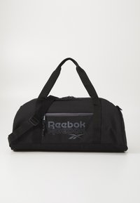 Bolsa de deporte negra hecha de tejido duradero, con un amplio compartimento principal, correa para el hombro ajustable y bolsillo delantero con cremallera con la marca Reebok.