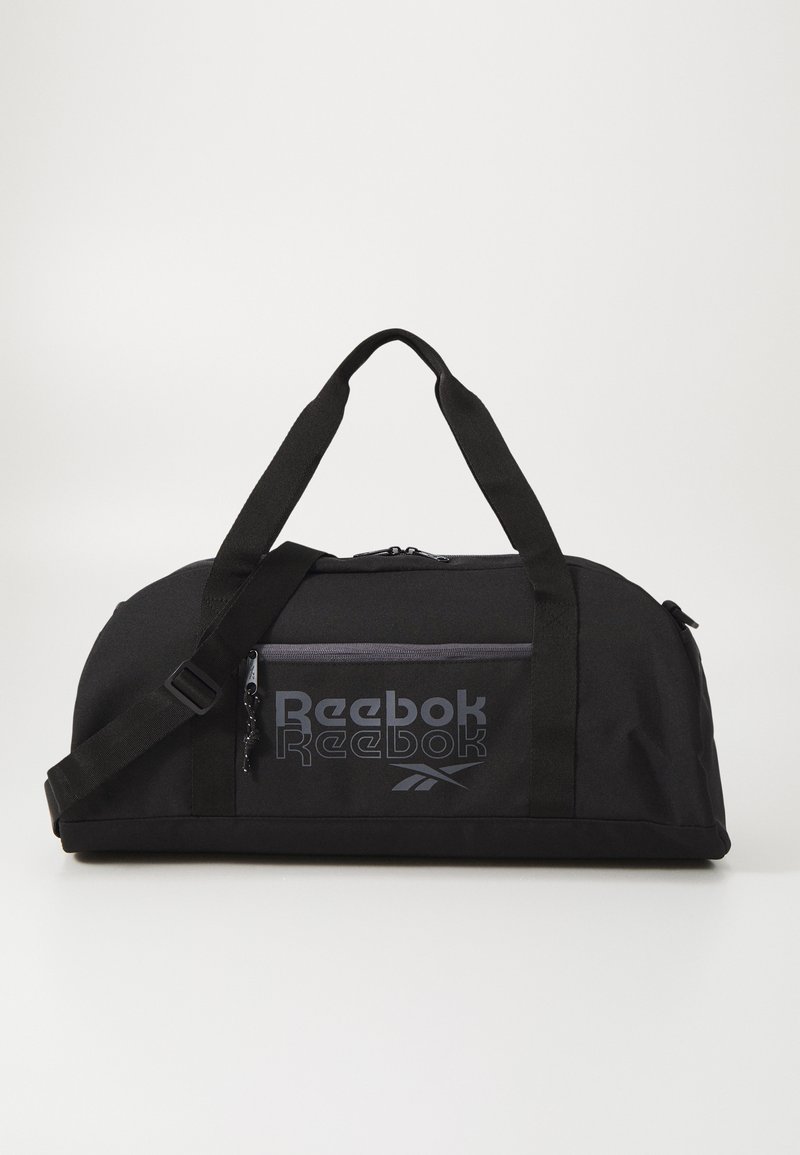 Bolsa de deporte negra hecha de tejido duradero, con un amplio compartimento principal, correa para el hombro ajustable y bolsillo delantero con cremallera con la marca Reebok.