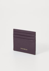 Violetter Leder-Kartenhalter mit vier Fächern, strukturierter Oberfläche und goldfarbener Logo-Akzentuierung. Kompaktes Design mit sauberen Stichdetails.