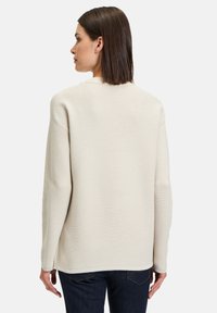 Hellbeige gerippter Strickpullover mit entspannter Passform, runder Ausschnitt und langen Ärmeln. Die Rückansicht zeigt eine horizontale Textur und überschnittene Schultern.